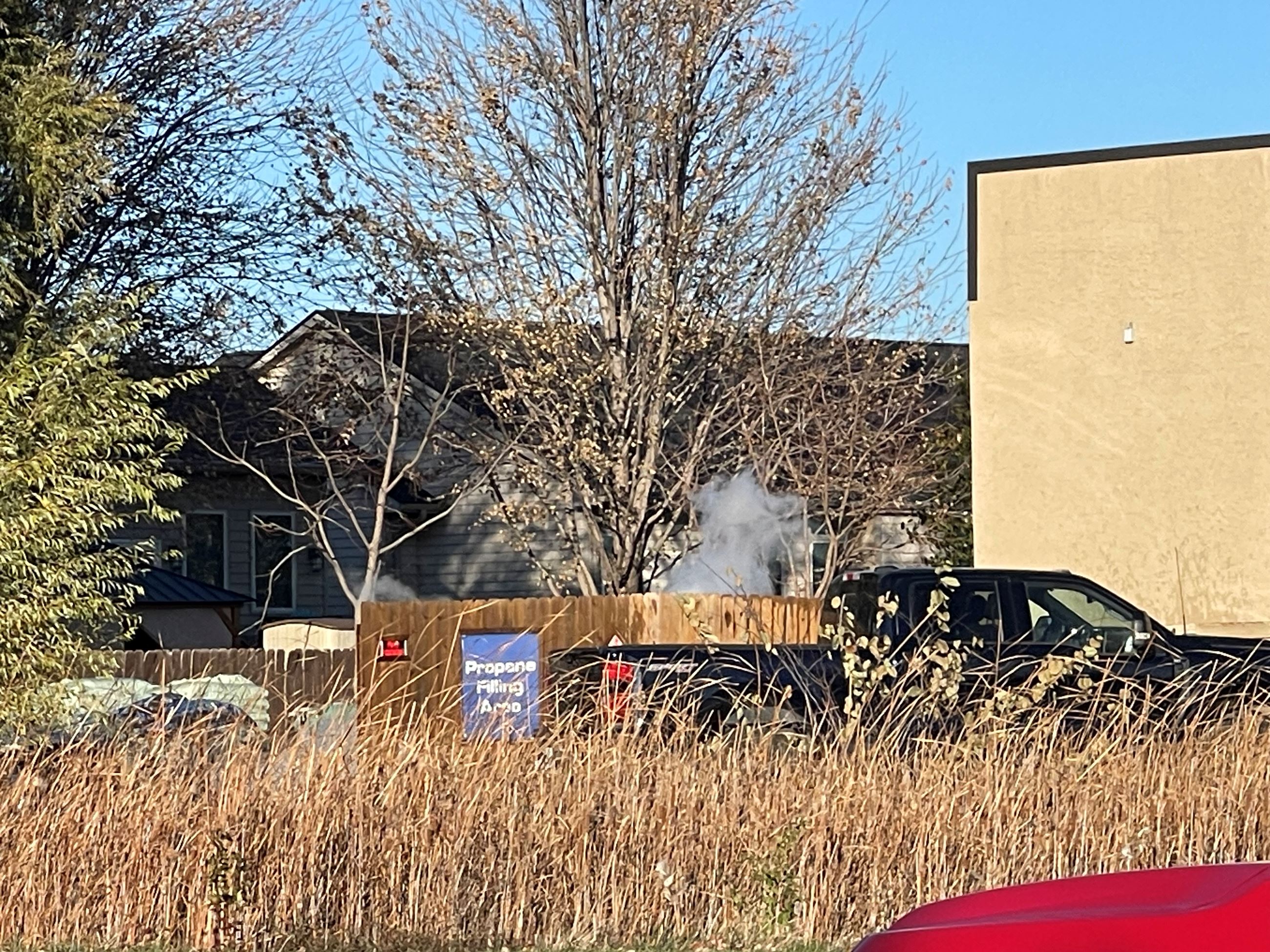White vapor cloud coming up from behind a fence at a hardware store